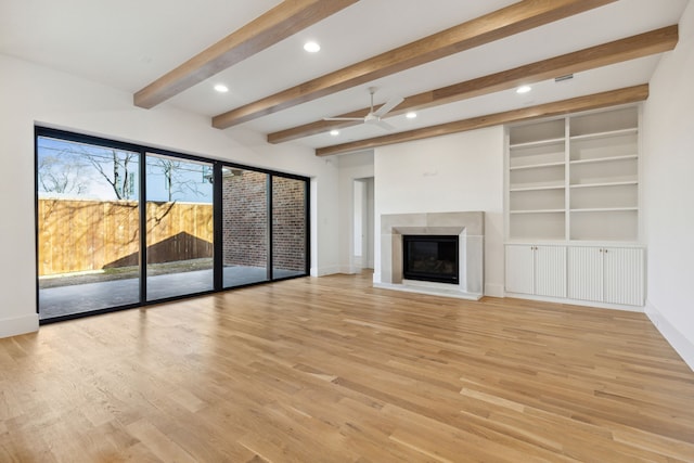 unfurnished living room featuring built in shelves, ceiling fan, light hardwood / wood-style flooring, and beamed ceiling