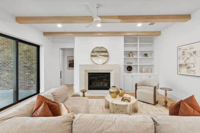 living room featuring ceiling fan, beam ceiling, light wood-type flooring, and built in features