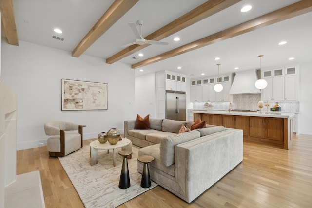 living room featuring ceiling fan, beamed ceiling, and light hardwood / wood-style floors