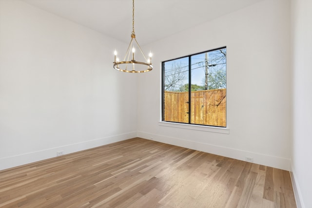 spare room with wood-type flooring and an inviting chandelier