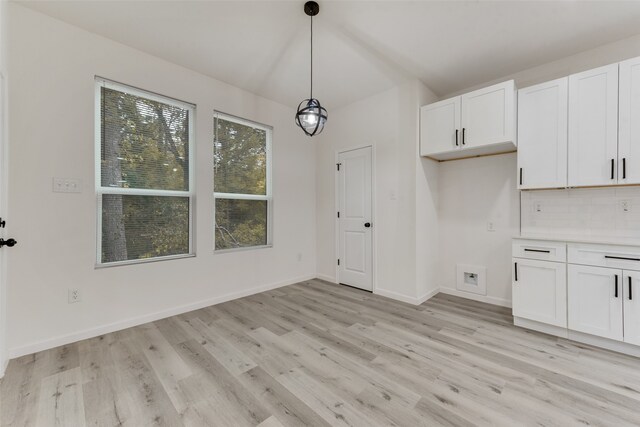 kitchen featuring pendant lighting, light wood-type flooring, backsplash, and white cabinetry