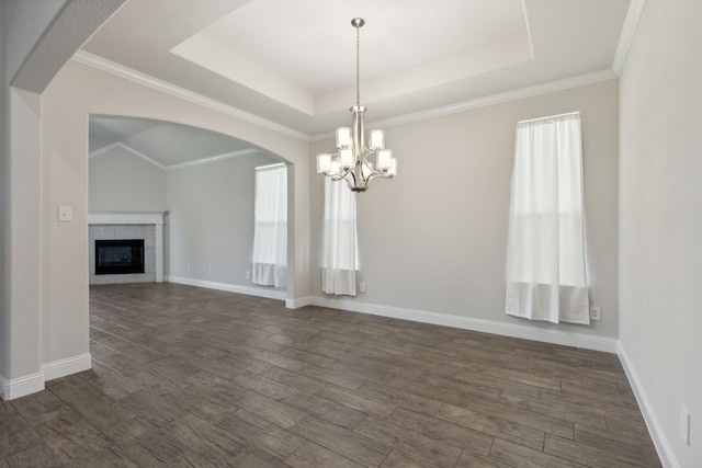 unfurnished dining area with dark wood-type flooring, a raised ceiling, a glass covered fireplace, and baseboards