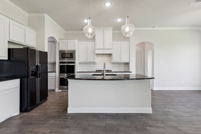 kitchen featuring white cabinets, stainless steel appliances, crown molding, decorative light fixtures, and a kitchen island with sink