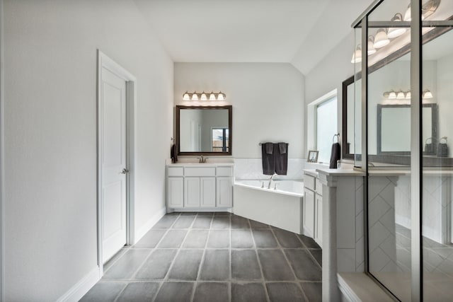 bathroom featuring baseboards, lofted ceiling, a garden tub, a shower stall, and two vanities