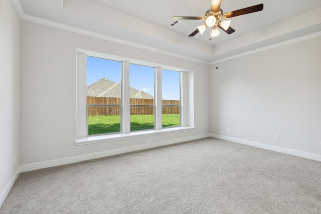 carpeted spare room featuring crown molding, a tray ceiling, and ceiling fan