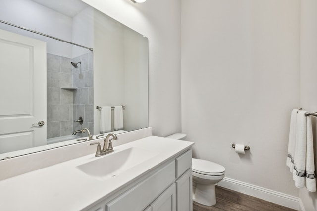 bathroom with baseboards, toilet, wood finished floors,  shower combination, and vanity