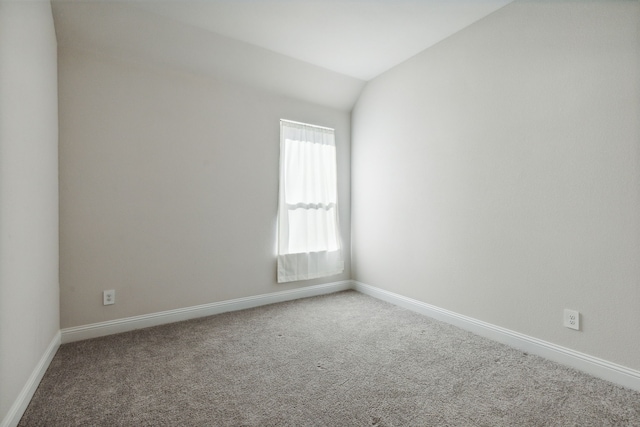 carpeted empty room with lofted ceiling and baseboards