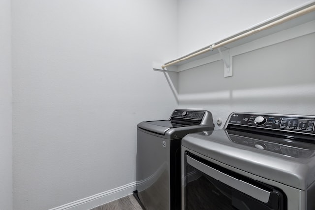 laundry room with laundry area, washer and clothes dryer, wood finished floors, and baseboards