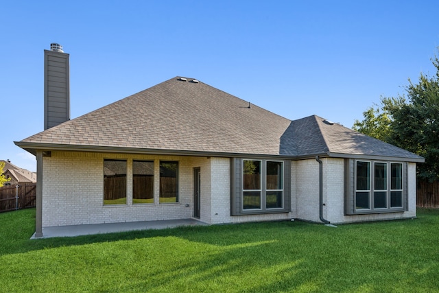 rear view of property featuring brick siding, a chimney, and a yard