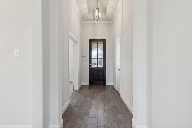 doorway with a notable chandelier, hardwood / wood-style floors, and crown molding