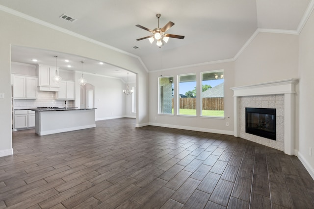 unfurnished living room featuring ceiling fan with notable chandelier, wood finish floors, lofted ceiling, and visible vents