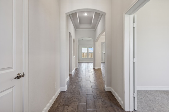 corridor with dark wood-style floors, baseboards, arched walkways, and ornamental molding