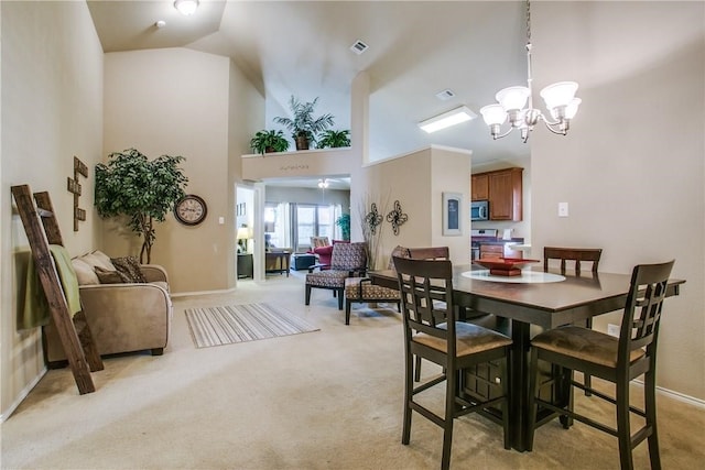 carpeted dining area with a notable chandelier and high vaulted ceiling