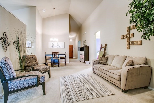 living room featuring high vaulted ceiling, light colored carpet, and an inviting chandelier