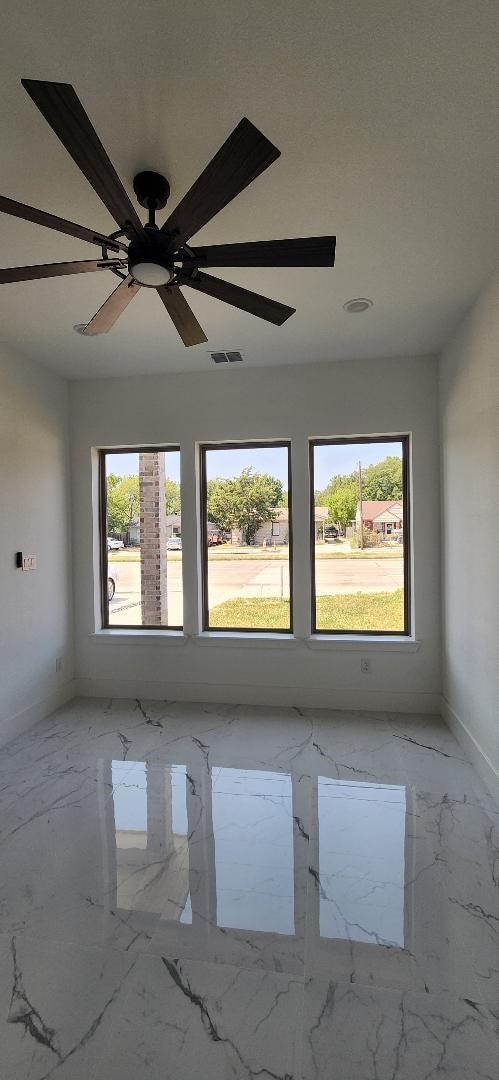 empty room featuring ceiling fan and a healthy amount of sunlight