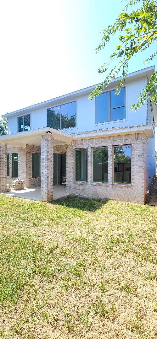 rear view of property with a lawn and a patio