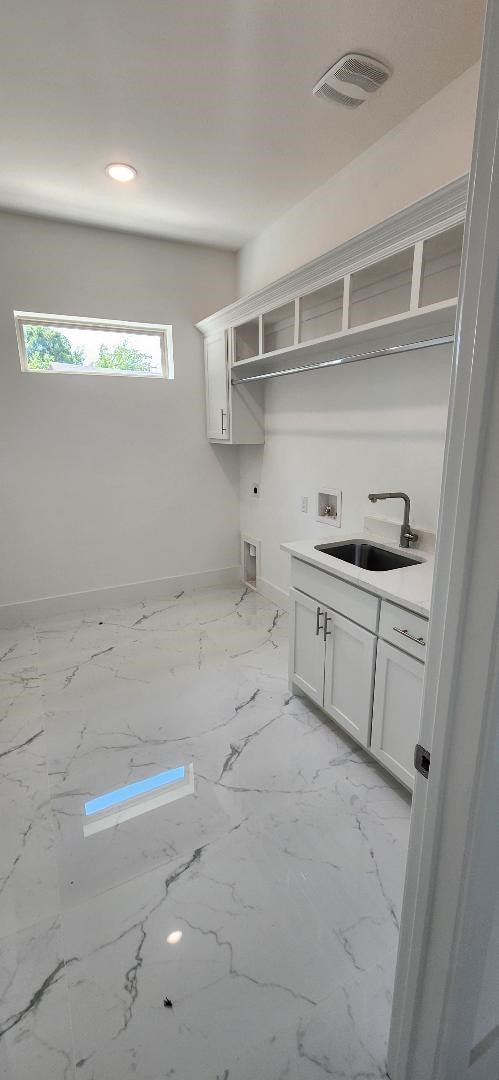 interior space with white cabinetry and sink