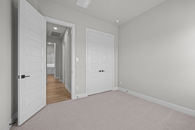 unfurnished bedroom with light colored carpet and a closet