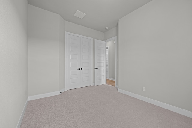 unfurnished bedroom featuring a closet and light colored carpet