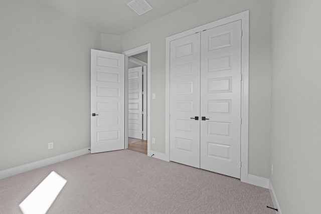 unfurnished bedroom featuring light colored carpet and a closet