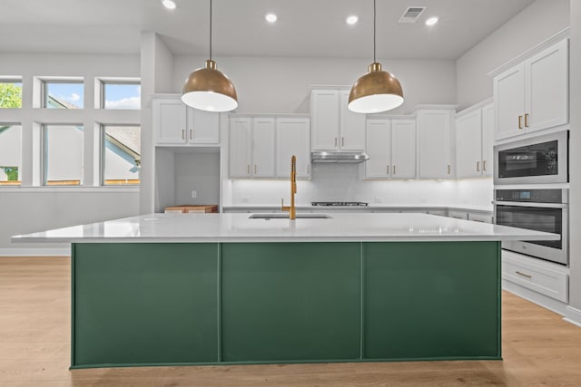 kitchen featuring white cabinets, oven, hanging light fixtures, and sink