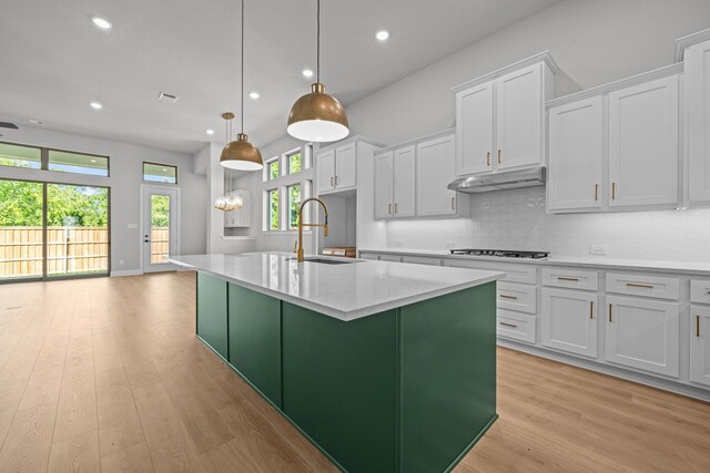 kitchen with a center island with sink, decorative light fixtures, sink, and white cabinets