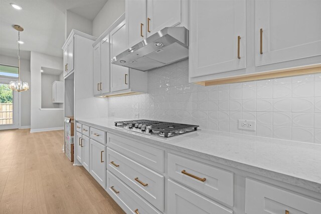 kitchen with pendant lighting, light wood-type flooring, light stone counters, white cabinetry, and stainless steel gas cooktop