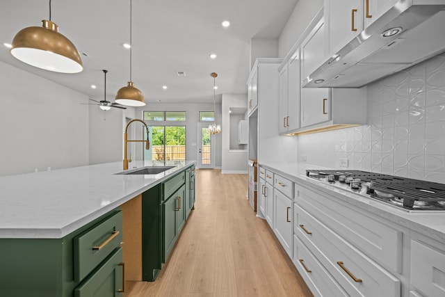 kitchen featuring a kitchen island with sink, sink, green cabinets, and white cabinetry