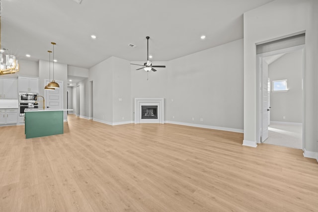 unfurnished living room with light wood-type flooring and ceiling fan