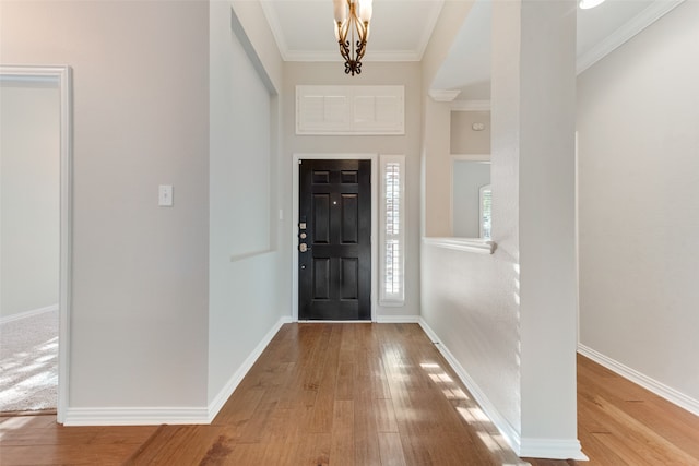 entrance foyer featuring an inviting chandelier, wood-type flooring, and crown molding