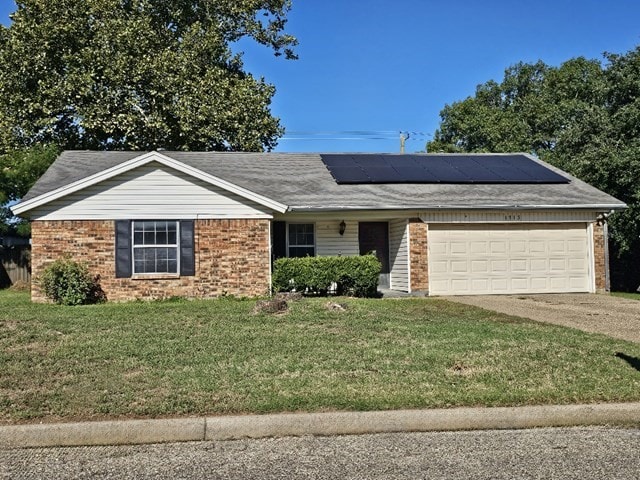 ranch-style house featuring a front yard, a garage, and solar panels