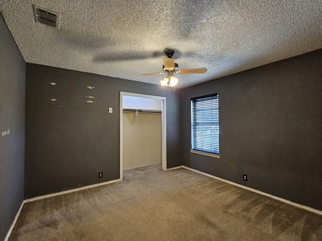 unfurnished bedroom featuring a textured ceiling, carpet floors, ceiling fan, and a closet