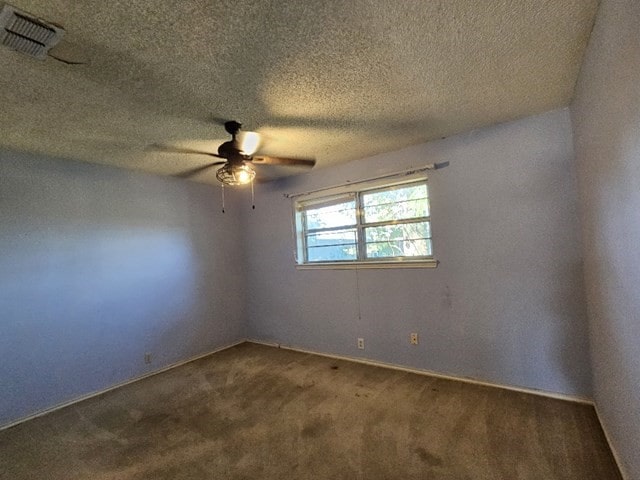 carpeted empty room with ceiling fan and a textured ceiling