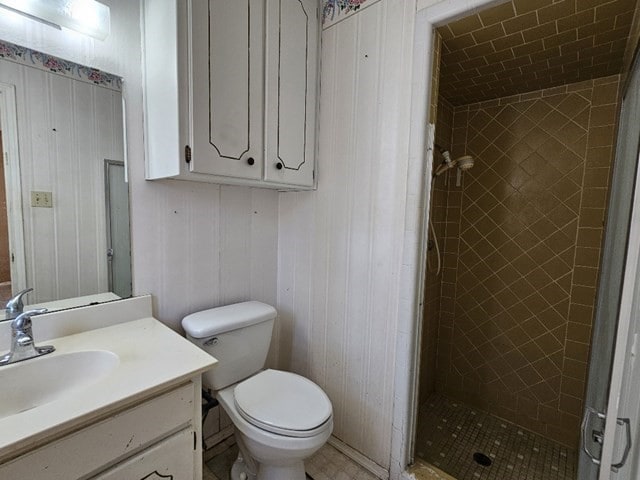 bathroom with toilet, vanity, and tiled shower