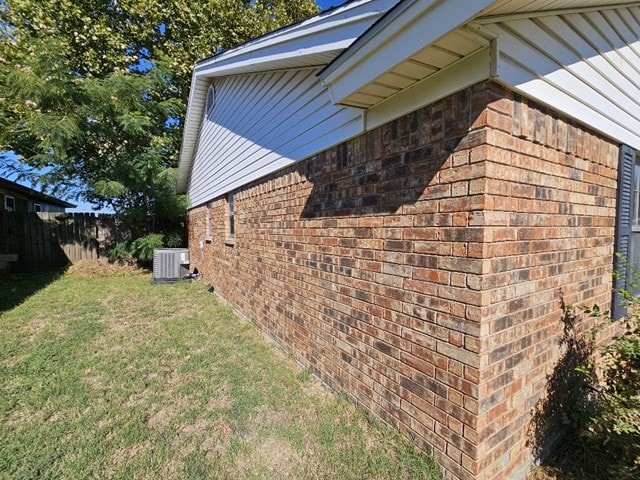 view of side of property featuring central AC and a yard