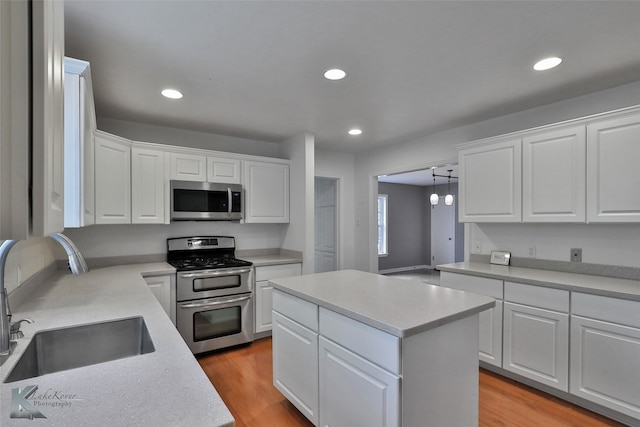 kitchen featuring stainless steel appliances, light wood-type flooring, sink, and white cabinetry