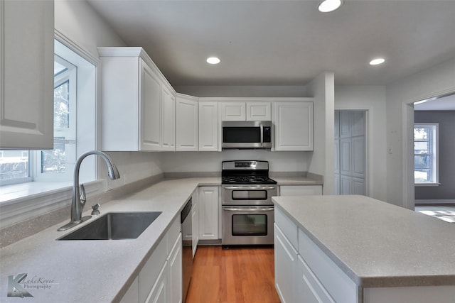 kitchen with appliances with stainless steel finishes, light wood-type flooring, sink, and a wealth of natural light