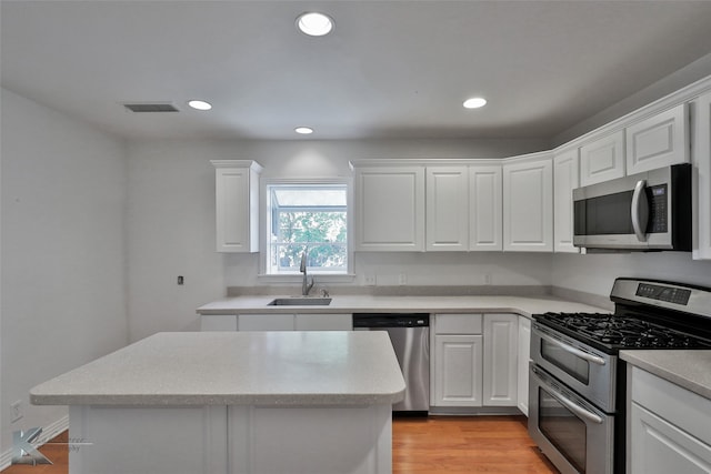 kitchen with light hardwood / wood-style floors, a center island, sink, white cabinets, and stainless steel appliances