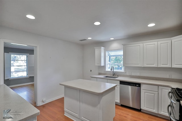 kitchen featuring white cabinets, a center island, appliances with stainless steel finishes, and sink