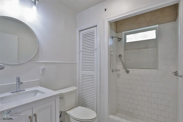 bathroom featuring a tile shower, vanity, and toilet