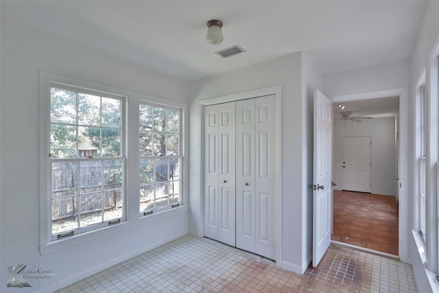 unfurnished bedroom with light tile patterned flooring, a closet, and multiple windows