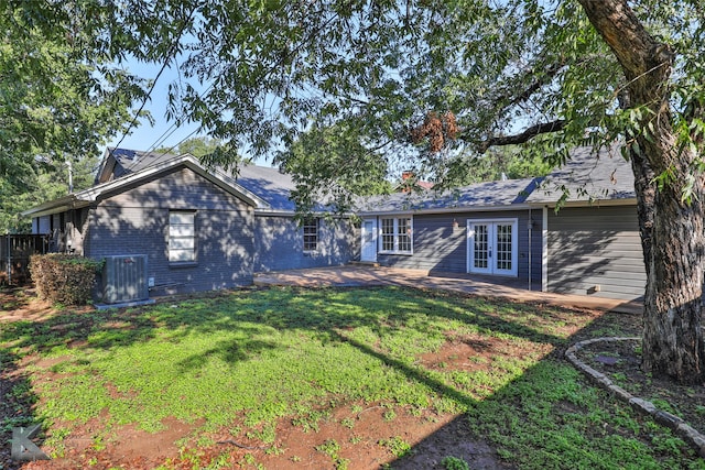 rear view of house featuring french doors, cooling unit, and a lawn