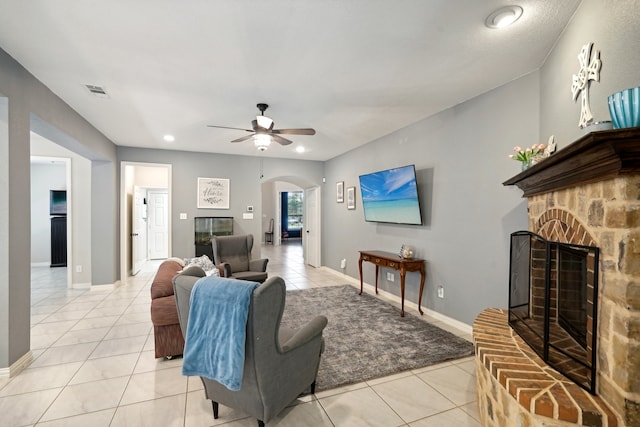 living room with a fireplace, light tile patterned flooring, and ceiling fan