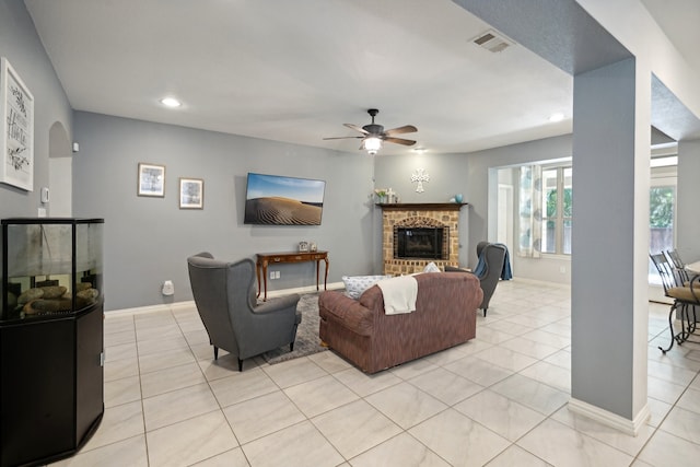 tiled living room featuring ceiling fan and a fireplace