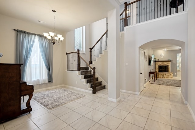 tiled foyer entrance with a notable chandelier, a fireplace, and a wealth of natural light