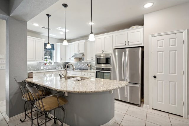 kitchen featuring light stone countertops, stainless steel appliances, white cabinetry, and pendant lighting