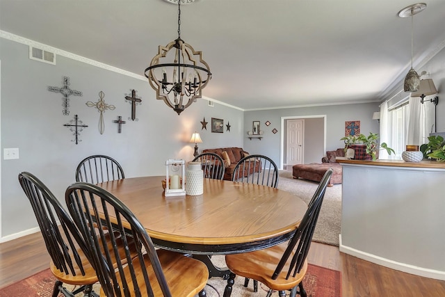 dining room with dark hardwood / wood-style flooring, crown molding, and an inviting chandelier