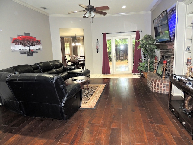 living room with a brick fireplace, ceiling fan with notable chandelier, dark hardwood / wood-style floors, and ornamental molding