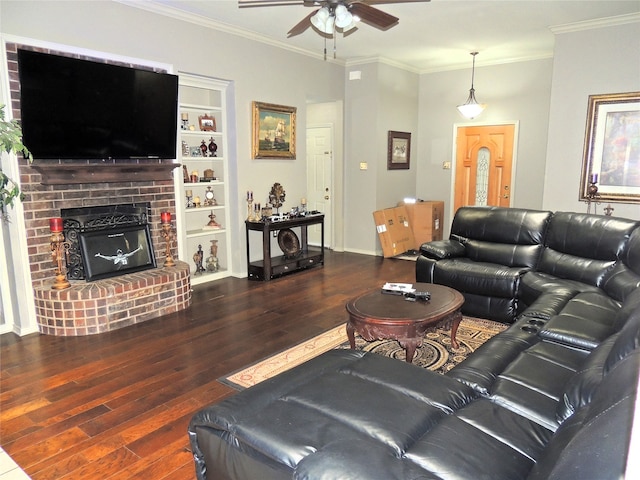 living room featuring a brick fireplace, dark wood-type flooring, ornamental molding, and ceiling fan