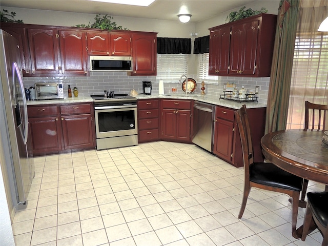 kitchen featuring backsplash, appliances with stainless steel finishes, light tile patterned floors, and sink